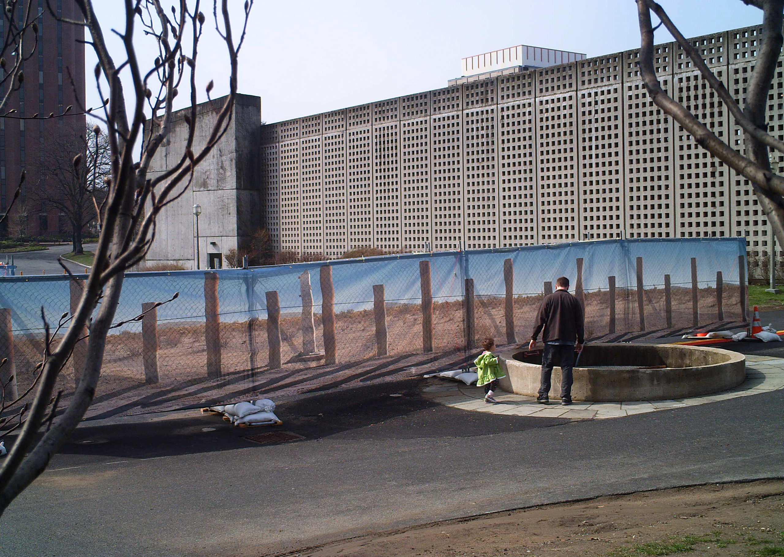A parent and child stand in front of an image of the souther border wall in the USA.
